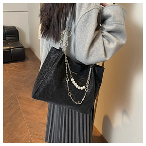 Close-up of black tote bag featuring leopard texture and elegant pearl chain detail