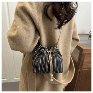 Detail of herringbone bucket bag with gold chain strap and pearl drawstring charm