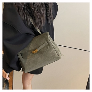 Detailed view of moss green suede briefcase bag with gold twist lock and strap