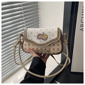 Close-up of a plaid shoulder bag with fruit embroidery and delicate bow detailing