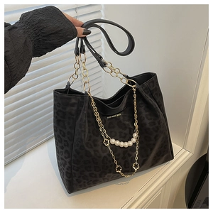 Detail of leopard print tote bag with gold chain, white pearls and floral charm pendant