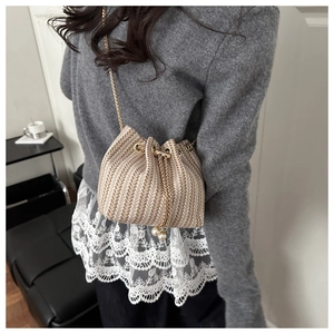 Close-up of beige woven bucket bag with elegant pearl drawstring and gold chain strap