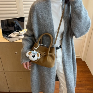 Sac bandoulière marron minimaliste au fini mat avec une jolie peluche de chiot