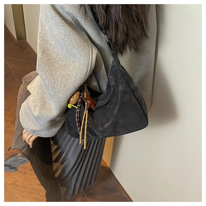 Détail du sac croissant en daim noir avec pendentif étoile et accessoire de corde tressée