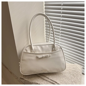 Détail d'un sac à bandoulière crème minimaliste avec nœud décoratif sur une couverture