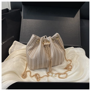 Detail of woven bucket bag with herringbone texture and elegant pearl drawstring