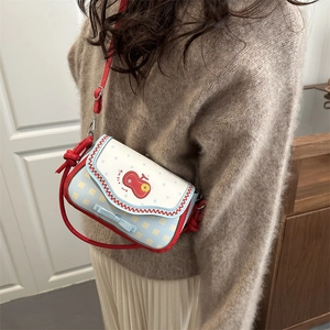 Sweet apple-shaped crossbody bag with polka dots and red bow on model