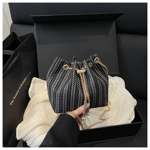 Detail of herringbone weave bucket bag with gold drawstring chain in a luxury gift box