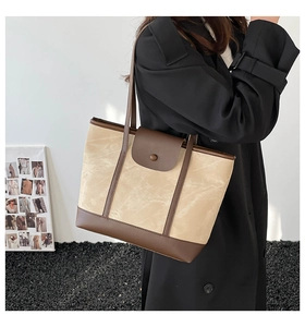 Detailed view of the large capacity canvas and brown leather tote bag on a model