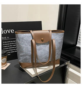 Macro detail of grey felt tote bag with brown leather handles and magnetic snap closure