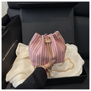 Detailed view of pink herringbone bucket bag with gold chain strap in a premium gift box