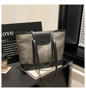 Detail of grey tote bag with black contrast flap button and large capacity design
