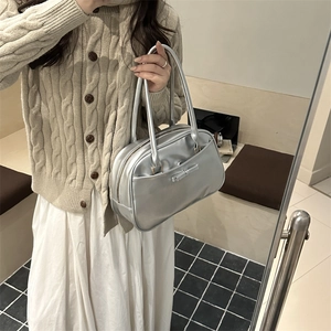 Silver metallic pillow handbag with bow detail shown on models outfit in a soft interior