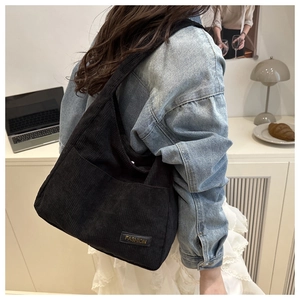 Detail of black corduroy tote bag with FASHION label shown in lifestyle setting