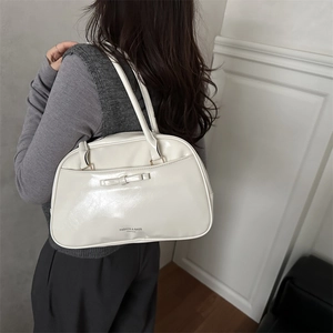 Cream white glossy patent leather underarm bag with bow detail and twin handles