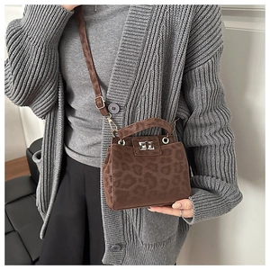 Detail of leopard print crossbody bag with metallic twist lock and adjustable strap