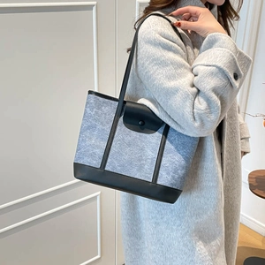 Grey suede minimalist tote bag with black leather straps shown on a model's shoulder