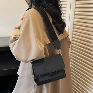 Minimalist black PU leather crossbody bag with wide strap styled with a beige trench coat