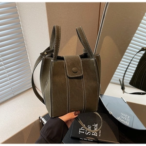 Detail of dark green bucket bag with white contrast stitching and adjustable strap