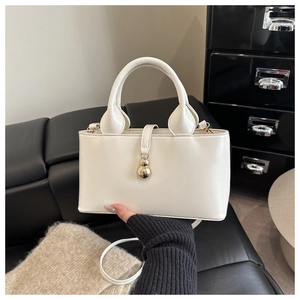 Détail d'un sac à main blanc en cuir avec pendentif doré et bandoulière réglable chic