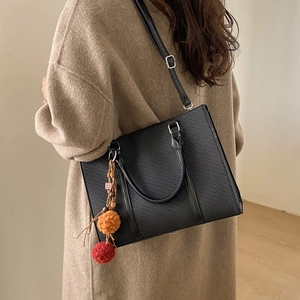 Minimalist black PU leather tote bag with silver hardware and colorful pompom charm