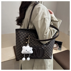 Détail d'un grand sac cabas marron avec motif M vintage et breloque nuage blanc