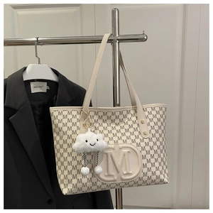 Détail du cabas beige avec monogramme lettre M et breloque en peluche nuage