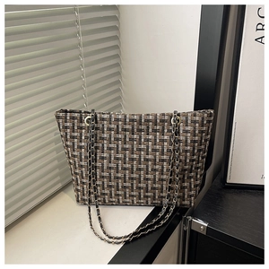 Detail of tweed tote bag featuring brown woven texture and gold chain strap
