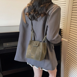 Olive green suede bucket bag with white contrast stitching and slim shoulder strap