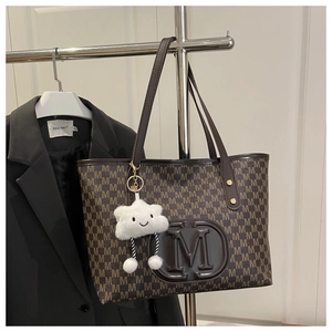 Détail du sac cabas marron avec motif à lettres M et charm en peluche nuage blanc