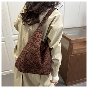 Close-up of leopard print canvas tote bag with wide strap worn over a trench coat