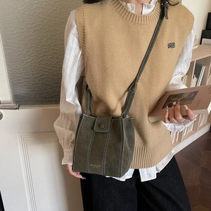 Olive green vintage crossbody bucket bag with white contrast stitching on model