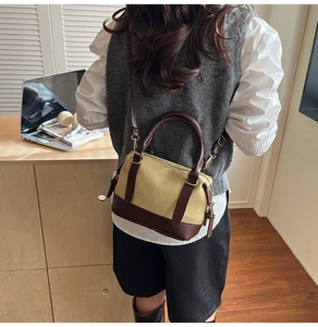 Détail du sac Boston rétro en toile beige et cuir marron porté par le mannequin