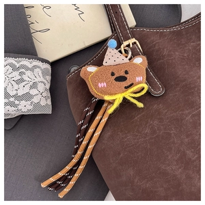 Detail of plush bear charm with stripes on a brown leather shoulder bag handle