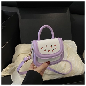 Detail of a purple and white mini crossbody bag featuring cherry prints and metal buckles