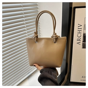 Détail de la poignée nouée d'un sac seau kaki en cuir synthétique dans un décor élégant