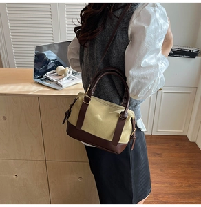 Détail du sac oreiller en toile et cuir contrastés avec bandoulière et doubles poignées