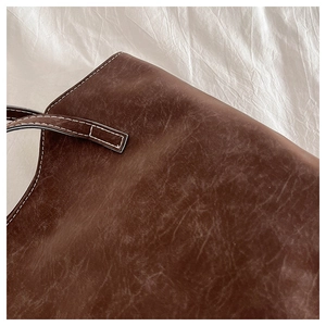 Detail of vintage brown tote bag featuring contrast white stitching and leather texture