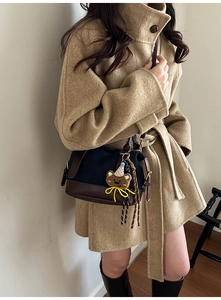 Detail of winter patchwork pillow bag with cute bear charm on beige wool coat