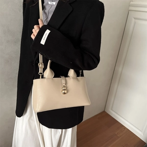 Sac seau minimaliste beige avec fermoir à boule dorée pour un style élégant et chic