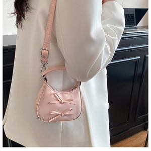 Détail du mini sac croissant rose avec double nœud décoratif sur tenue blanche
