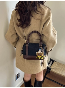 Detail of vintage canvas pillow bag with brown leather trim and cute bear charm accessory