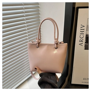 Détail d'un sac seau rose avec poignée nouée et bandoulière amovible en cuir synthétique