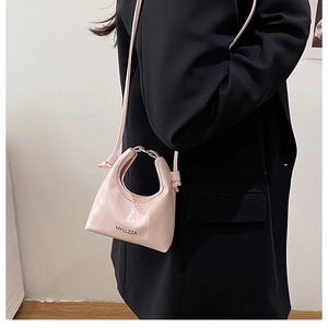 Detail of pink patent leather crossbody bag with round hollow handle and logo