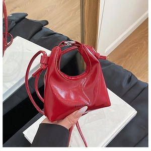 Detail of red patent leather mini handbag featuring a glossy finish and knotted handle
