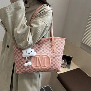 Pink tote bag with letter M print and cloud charm worn by model in casual style