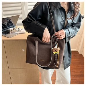 Close-up of vintage brown leather tote bag with contrast stitching and bear charm