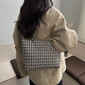 Fashionable tweed chain tote bag in black and brown worn by a model in a trench coat