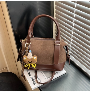 Détail d'un sac oreiller marron foncé avec breloque ours sur magazine Super Normal