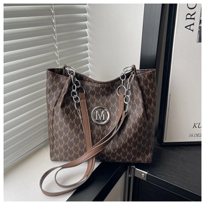 Close-up of brown monogram tote bag with silver M logo and stylish chain strap detail